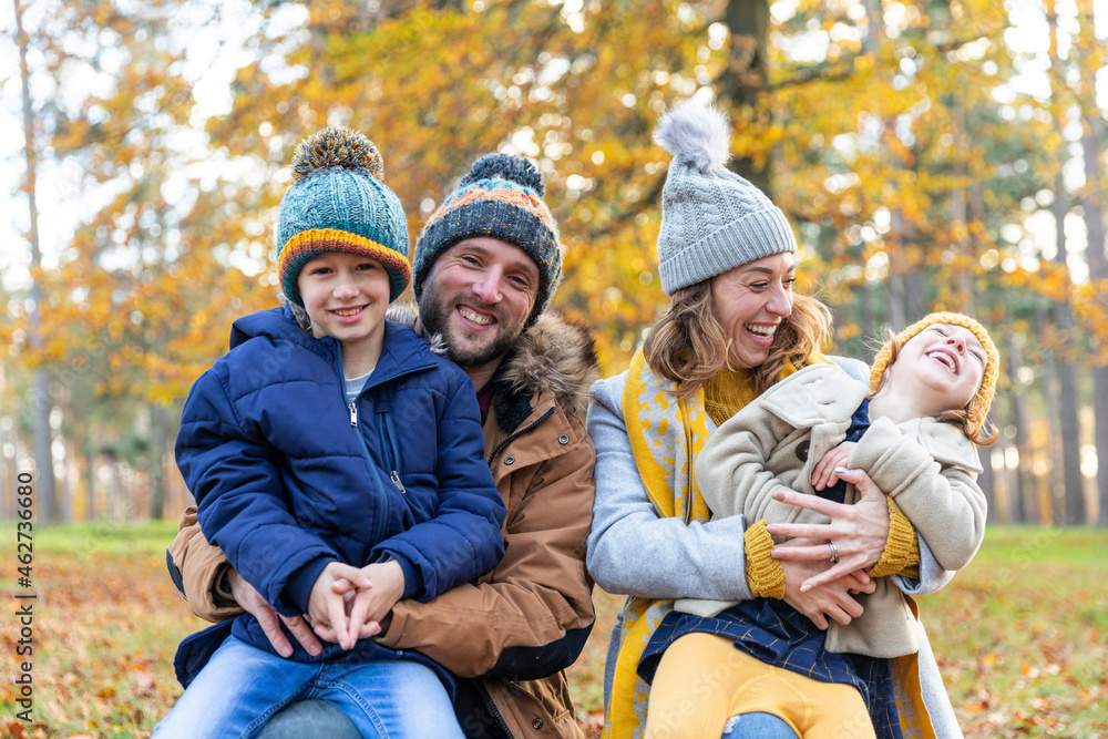 Cheerful parents smiling while sitting with children at forest Cheerful parents smiling while sitting with children at forest