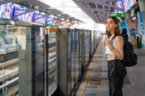 Portrait of Beautiful Asian woman tourist waiting for skytrain at railway station platform in the city. Confidence female enjoy city life with outdoor lifestyle travel and shopping at summer time photo
