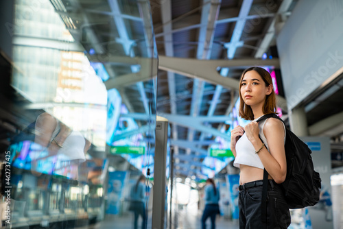 Portrait of Beautiful Asian woman tourist waiting for skytrain at railway station platform in the city. Confidence female enjoy city life with outdoor lifestyle travel and shopping at summer time