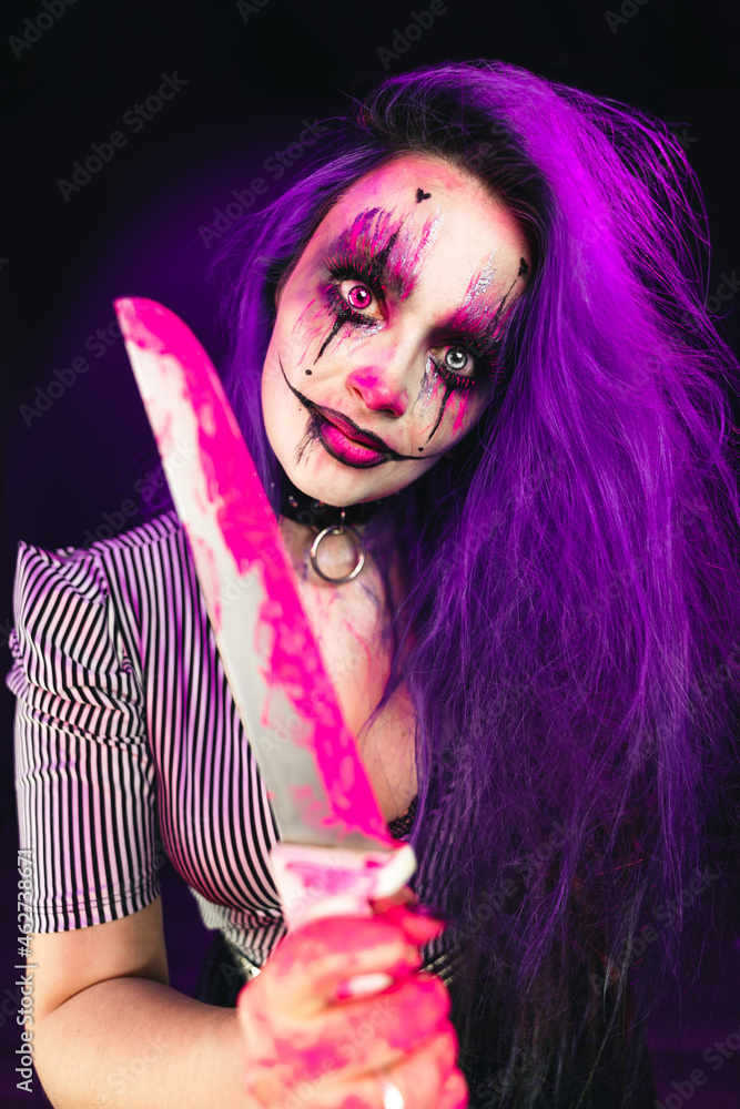 Young woman with scary halloween makeup big eyes colored purple hair and dark background