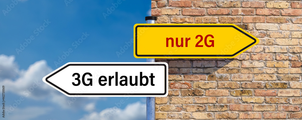 signpost with German message for ONLY RECOVERED AND VACCINATED and another one meaning the 3 options TESTED, RECOVERED AND VACCINATED in front of a brick wall signpost with German message for ONLY RECOVERED AND VACCINATED and another one meaning the 3 options TESTED, RECOVERED AND VACCINATED in front of a brick wall