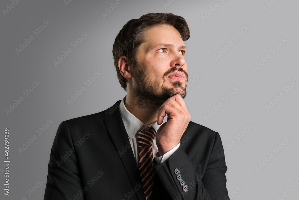 thinking businessman in front of a grey wall thinking businessman in front of a grey wall