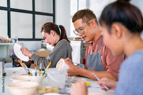 Fotografia, Obraz Group of Asian man and woman millennial generation friends enjoy and having fun painting self-made pottery together at pottery studio
