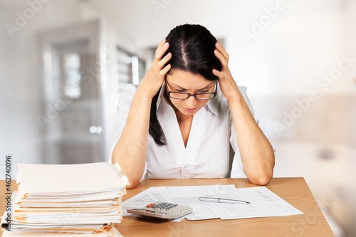 A young woman in eyewear paying household bills taxes or insurance, managing budget, calculating expenses.