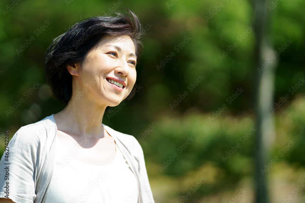 緑の中を散策する笑顔の中年女性 さわやかなミドル女性 緑の中を散策する笑顔の中年女性 さわやかなミドル女性