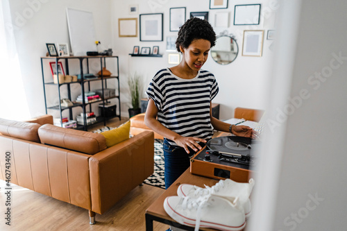 Young woman using record player at home photo