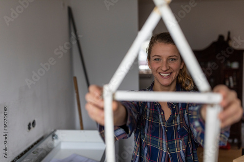 Happy young woman holding pocket rule in shape of a house