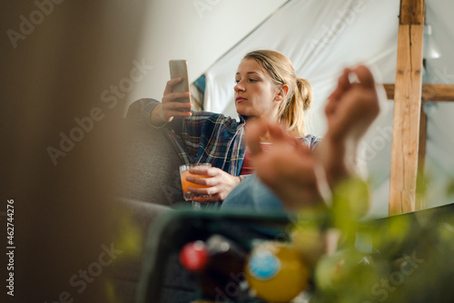 Relaxed young woman sitting on couch looking at cell phone