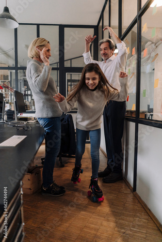 Businessman and businesswoman with girl on roller skates in office photo
