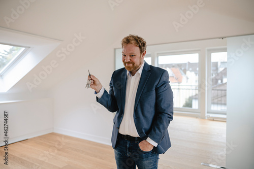 Portrait of smiling businessman standing in empty apartement holding key photo