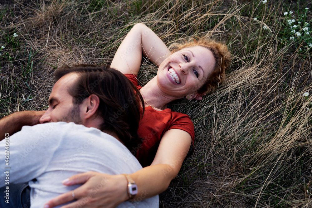 Happy couple cuddling, lying on a meadow Happy couple cuddling, lying on a meadow