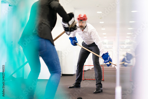 Businesswoman and businessman playing ice hockey in office photo