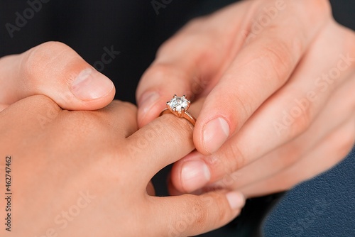 a man puts a wedding ring on his finger, the concept of cheating man. © BillionPhotos.com