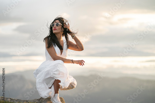 Young woman wearing white dress on viewpoint at sunset photo