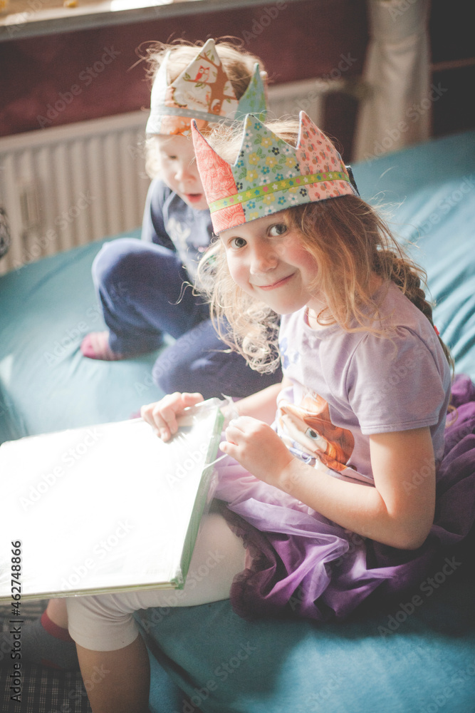 Two sisters wearing crowns and unpacking presents on bed Two sisters wearing crowns and unpacking presents on bed