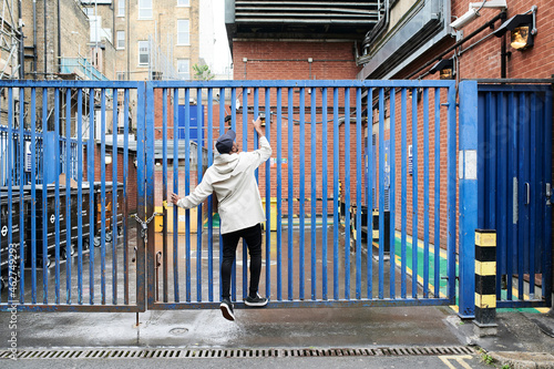 Back view of man climbing gate