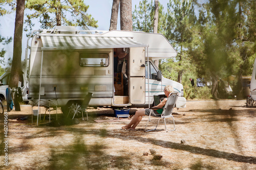 France, Gironde, woman sitting in front of camper on a camping ground using digital tablet photo