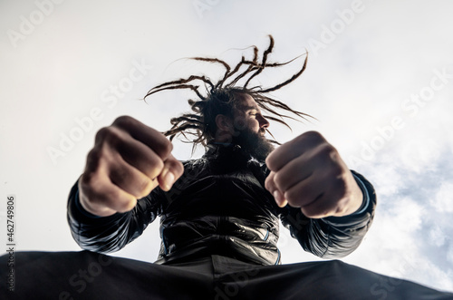 Bearded man with dreadlocks clenching fists photo