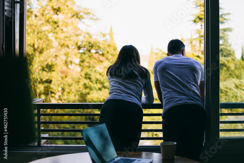 Couple leaning on balcony railing while standing at home photo