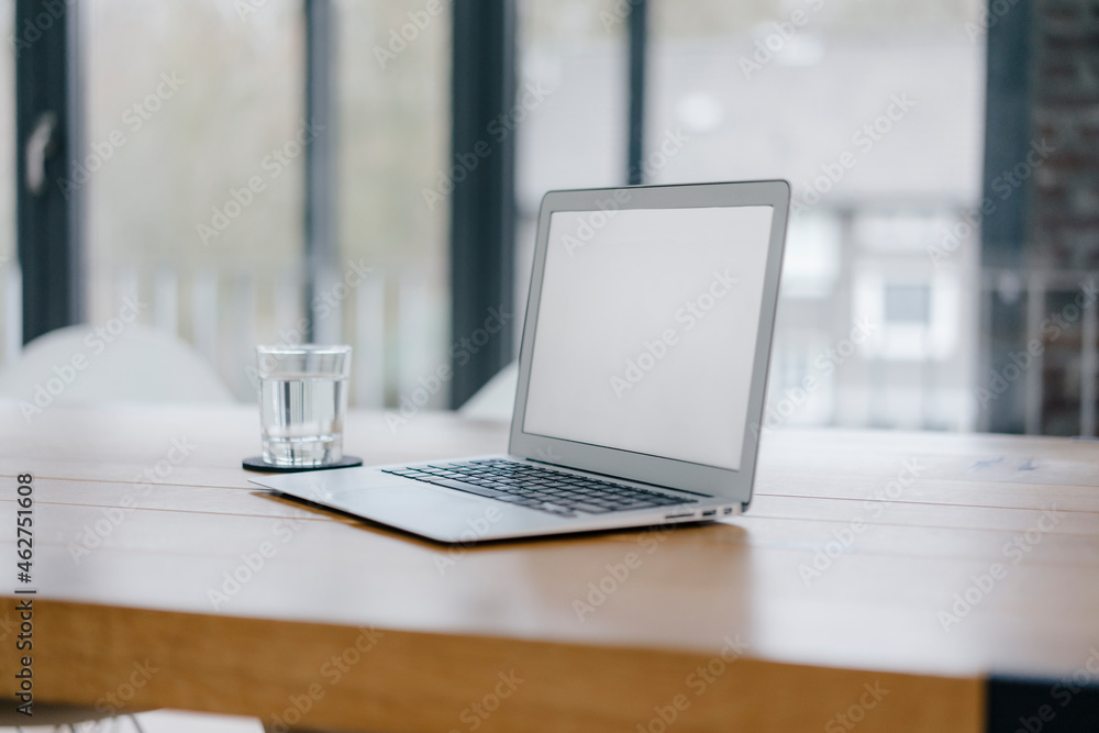 Laptop on desk in office with glass of water Laptop on desk in office with glass of water