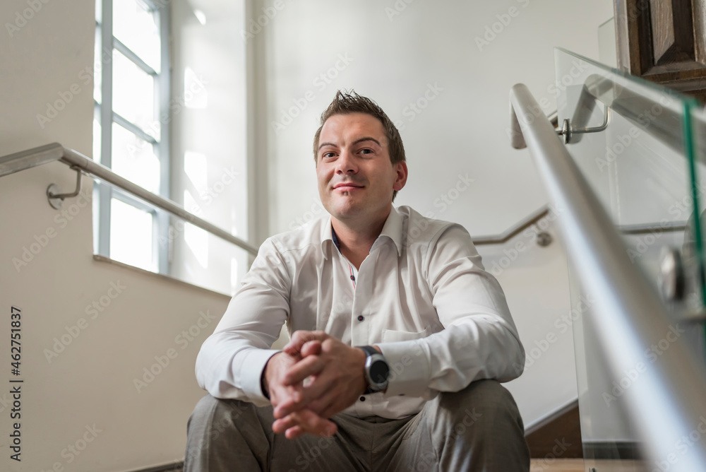Portrait of confident businessman sitting in staircase Portrait of confident businessman sitting in staircase