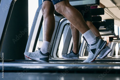 Legs of athletes running on treadmills in health club © Westend61