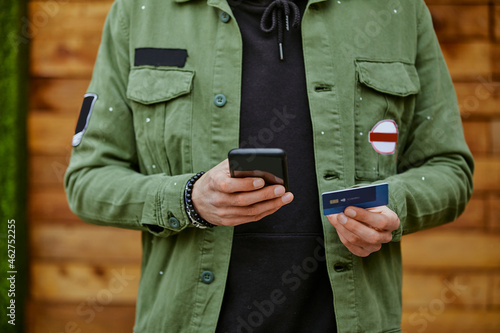 Man in jacket holding smart phone while doing online payment through credit card photo