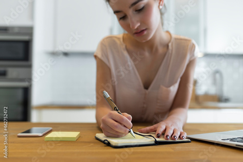Female teenager writing in her calender in the kitchen photo
