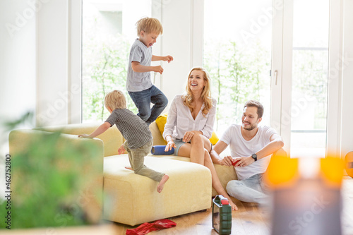 Happy family in living room of their new home with boys romping about