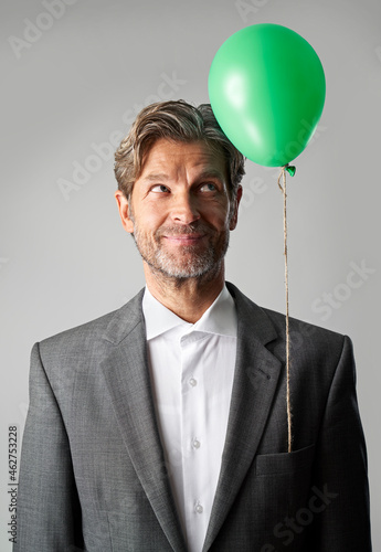 Portrait of smiling businessman with green balloon