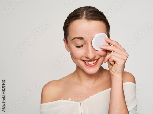 Portrait of smiling young woman with cotton pad on her eve photo