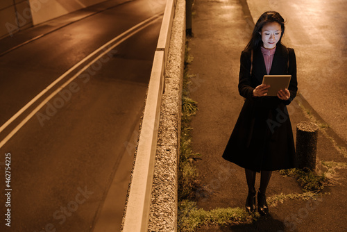 Young woman using tablet in the city at night, Frankfurt, Germany