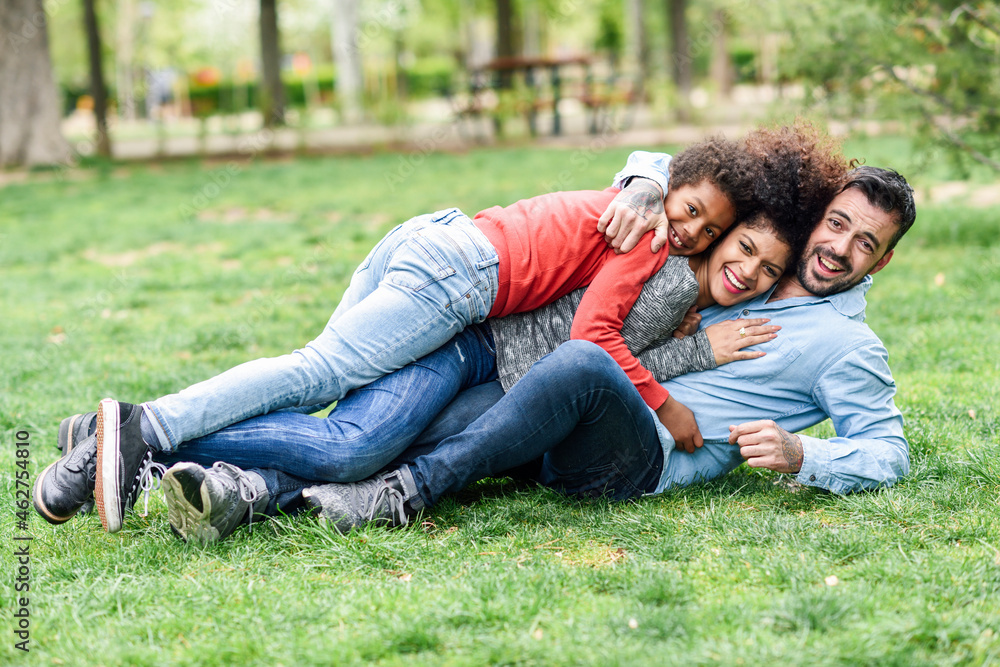 Happy family embracing, lying on grass in a park Happy family embracing, lying on grass in a park