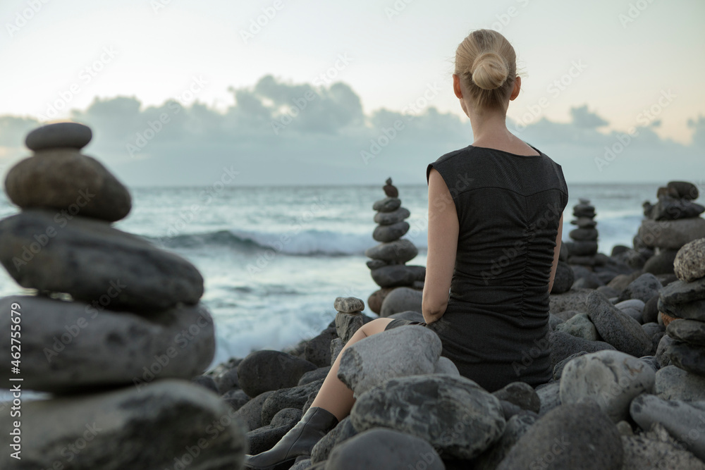 Spain, Tenerife, Costa Adeje, woman sitting between cairns at the coast Spain, Tenerife, Costa Adeje, woman sitting between cairns at the coast