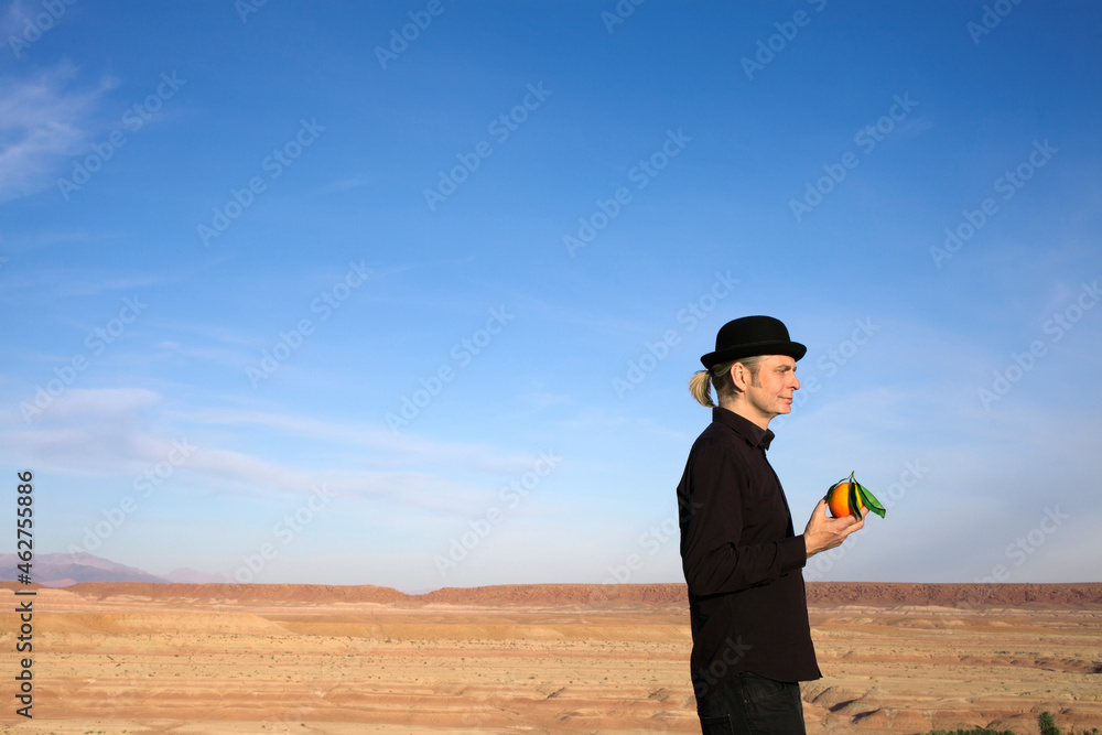 Morocco, Ounila Valley, man wearing a bowler hat holding an orange Morocco, Ounila Valley, man wearing a bowler hat holding an orange