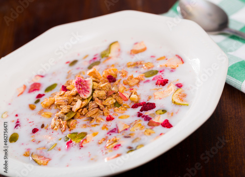 Oatmeal with dried fruit and milk in a plate. Tasty breakfast photo