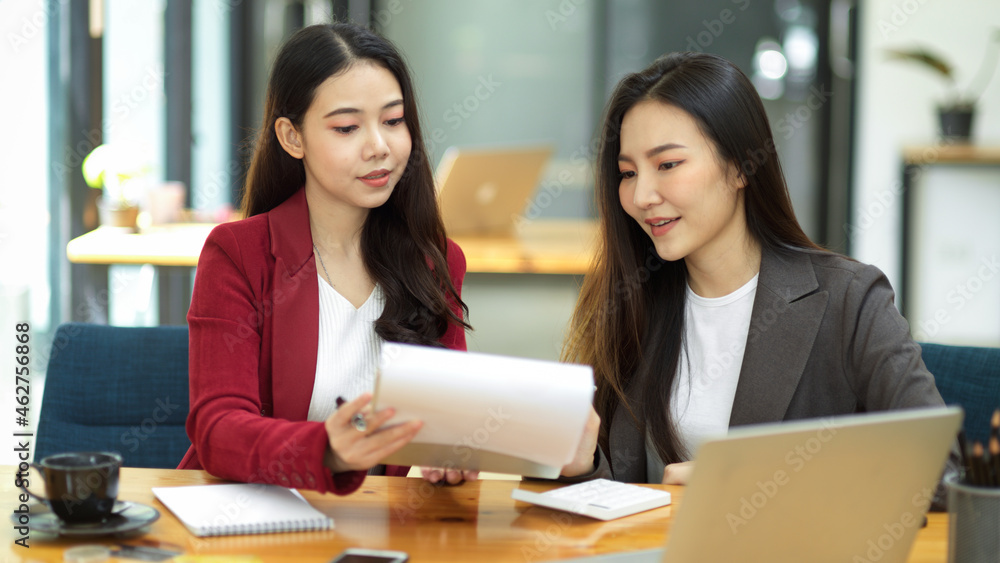 Two young smart business women working together on financial documents Two young smart business women working together on financial documents