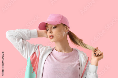 Photography Young woman in baseball cap touching hair on pink background