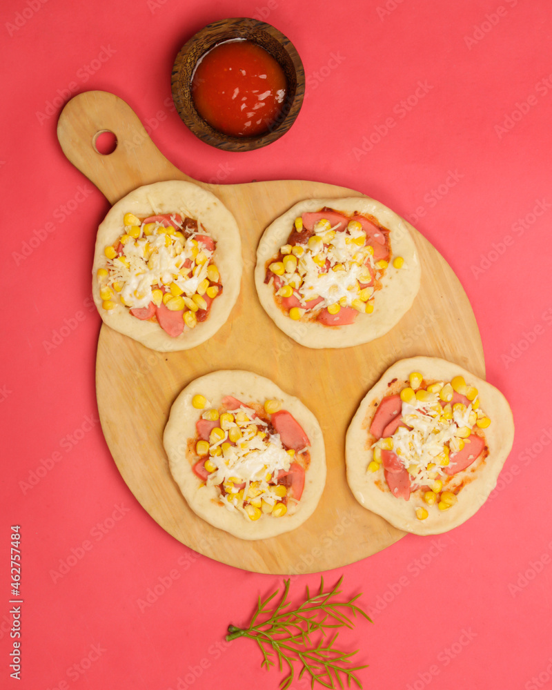 Mini pizza with corn, sausage and cheese topping for your lunch menu. pizza is a savory dish from Italy a kind of round and flat dough, baked in the oven. Pizza mockups. Focus blur. Focus on some ange
