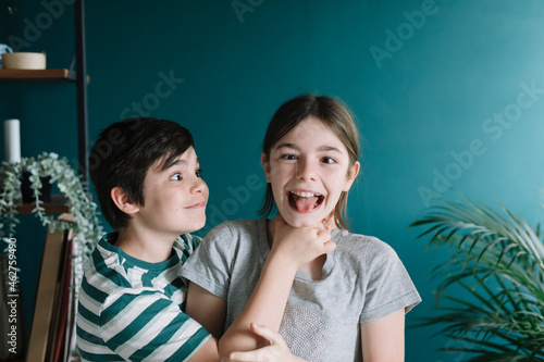 Playful boy strangling sister's neck against wall at home photo