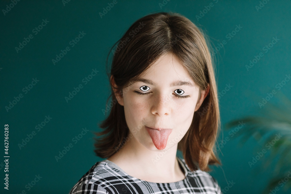Close-up of girl with googly eyes and make-up sticking out tongue against wall at home Close-up of girl with googly eyes and make-up sticking out tongue against wall at home