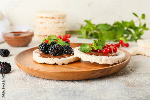 Plate with puffed rice crackers and berries on light background, closeup