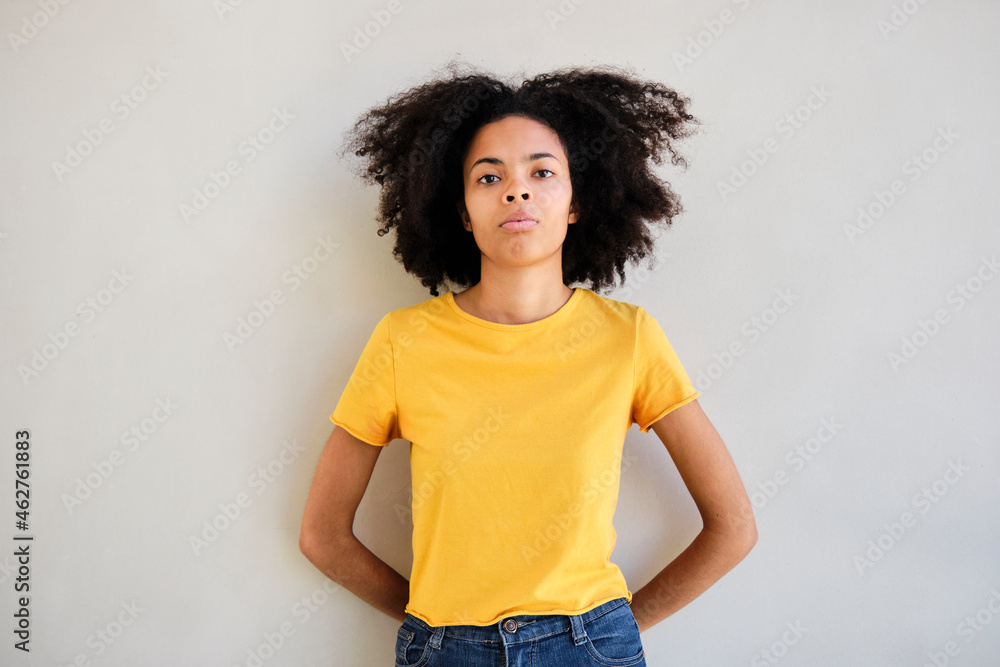 Young student standing with hands behind head against wall Young student standing with hands behind head against wall