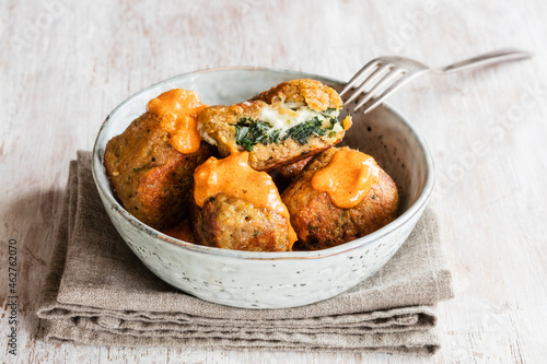 Bowl of fried spinach balls with tomato sauce photo
