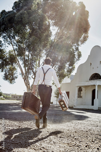 Man in old-fashioned clothes with suitcases in the countryside photo