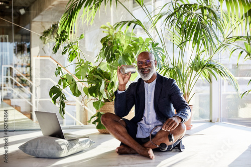 Mature man using tin can phone while holding headphone sitting at home