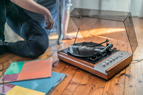Close-up of man sitting on the floor at home with a record player photo