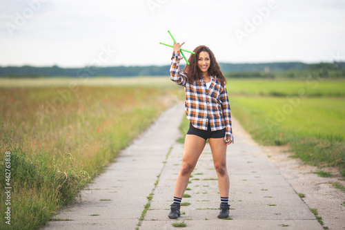 Happy woman with drumsticks standing on road in field photo