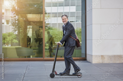 Wallpaper Mural Businessman on e-scooter passing office building in the city Torontodigital.ca