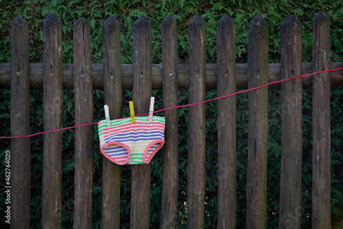 Colorful underpants drying on clothesline in front of wooden fence